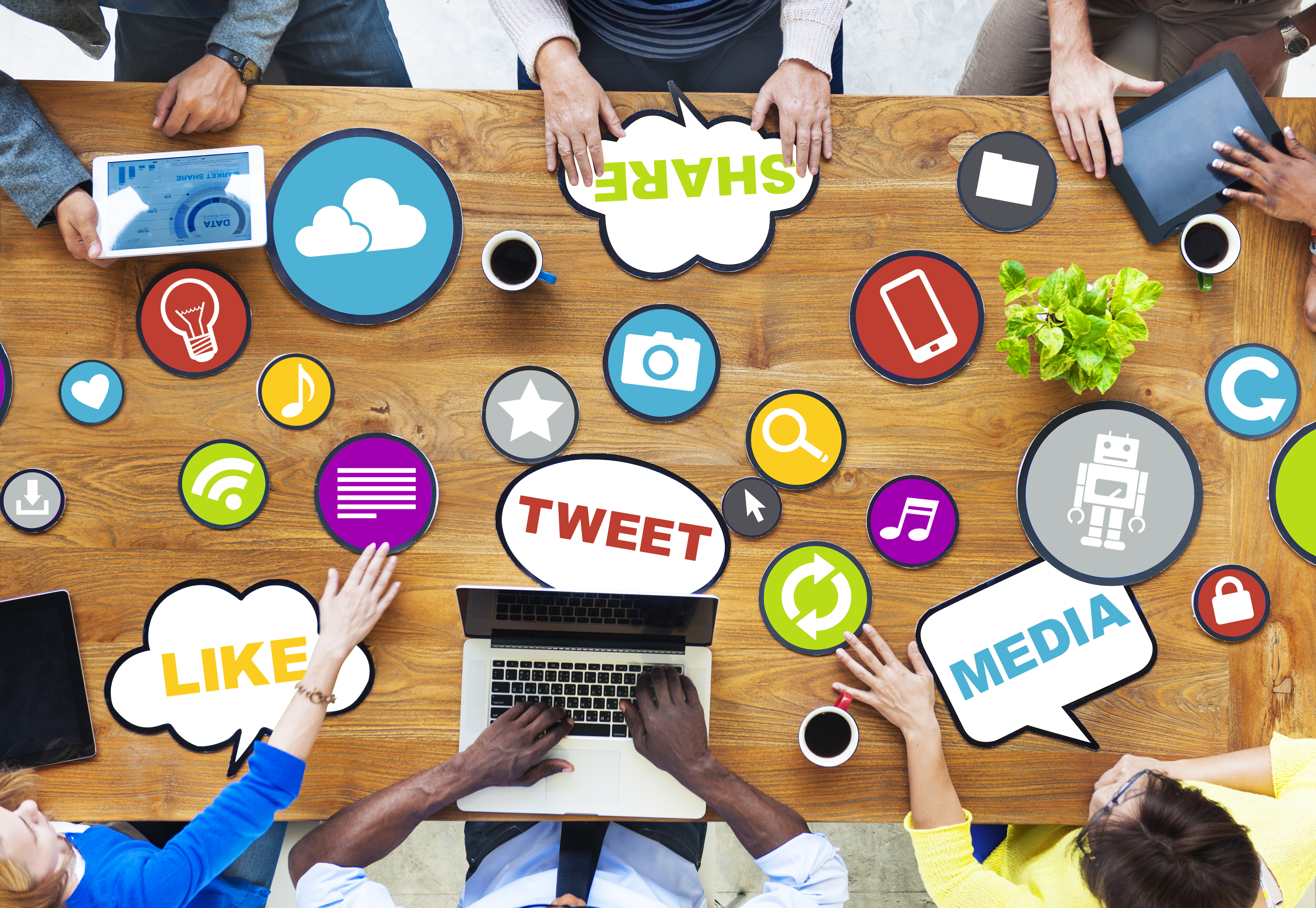 people having meeting around table holding tablets and table top covered in media stickers